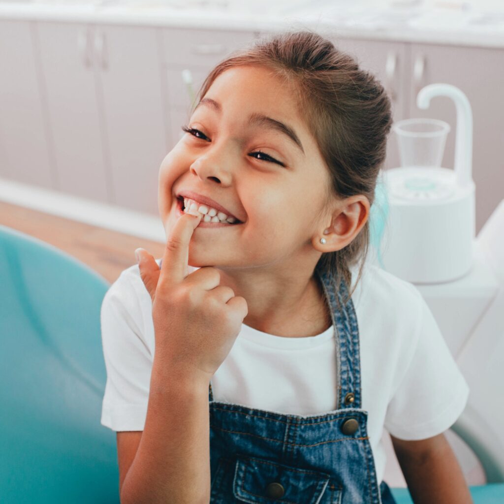 A little girl pointing to a tooth that may need extraction.