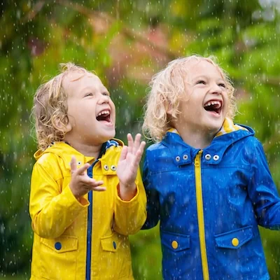 Kids play in autumn rain. Child playing outdoor on rainy day. Little boy catching rain drops under heavy shower. Fall storm in a park. Waterproof wear for kid. Children outdoors by any weather.